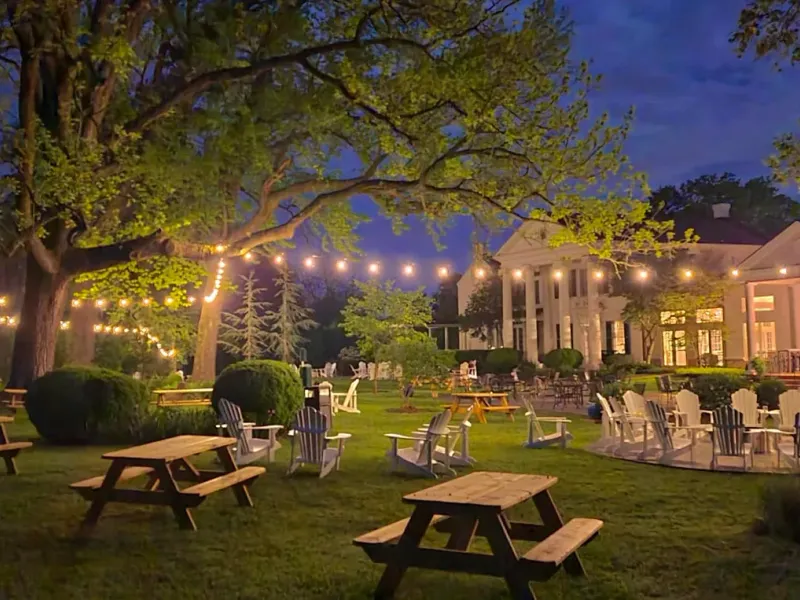 Outdoor patio and lawn at Bluemont Station Winery & Brewery lit by string lights at dusk