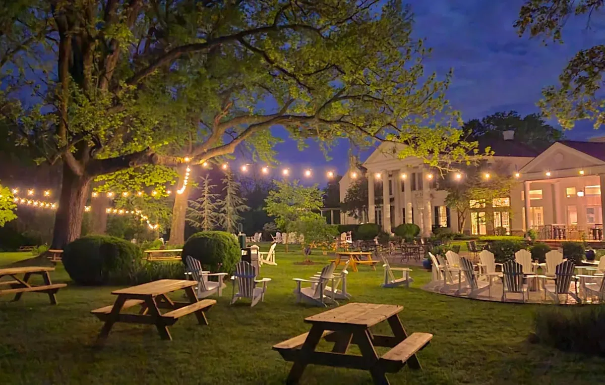 Outdoor patio and lawn at Bluemont Station Winery & Brewery lit by string lights at dusk