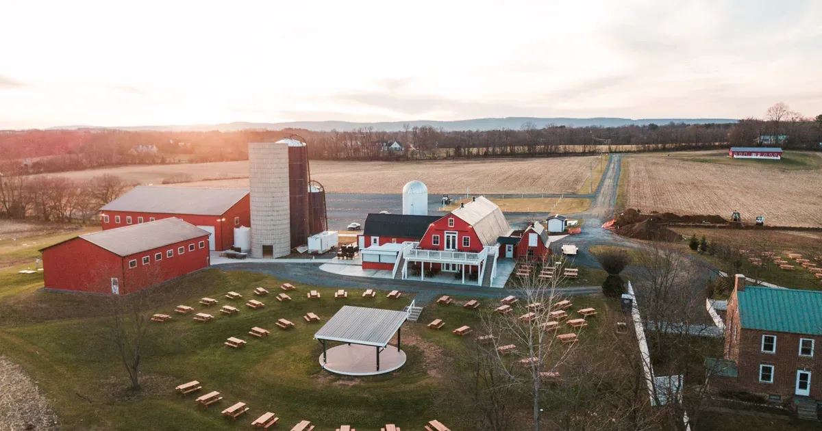 Aerial view of Flying Ace Farm Brewery and Distillery with its red barns, tasting building, and outdoor seating lawn