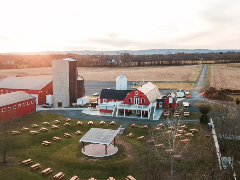 Aerial view of Flying Ace Farm Brewery and Distillery with its red barns, tasting building, and outdoor seating lawn