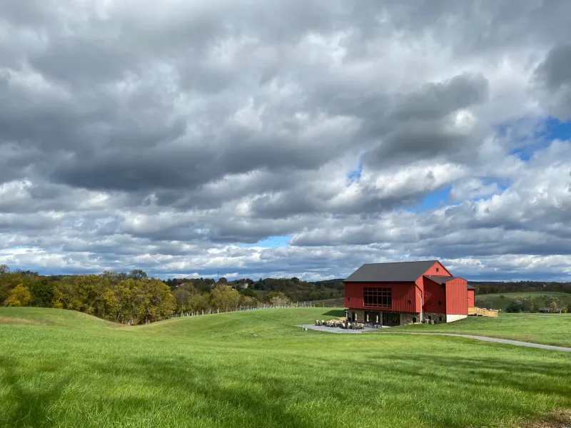 Terra Nebulo Vineyards red barn on rolling hills under dramatic clouds